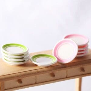 Stacks of miniature plates with green and pink rims on a wooden table.