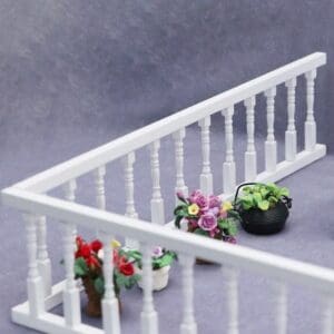 White railing with potted flowers, including red, purple, and green plants, on a gray background.