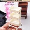 Miniature white three-tier cart on hand, with colorful variations in the background.