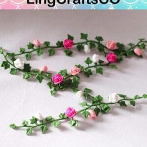 Colorful paper flower vines with pink, white, and green leaves on a light surface.