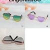 Three heart-shaped sunglasses: green-yellow, purple, and black lenses displayed on a surface and notebook.