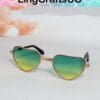 Heart-shaped sunglasses with gradient green-yellow lenses and gold frames, displayed on a white surface.