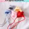 Five colorful crocheted hats with earflaps on a white background, featuring red, pink, blue, yellow, and gray colors.