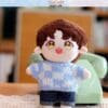 Cute plush doll with brown hair, wearing a blue sweater, standing in front of a vintage green phone.