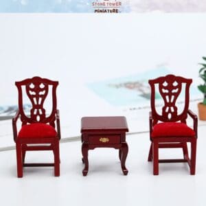 Two miniature red wooden chairs with red cushions flank a small wooden table on a white surface.