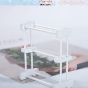 White miniature drying rack on a blurred magazine background with a "Stone Tower Miniature" logo at the top.