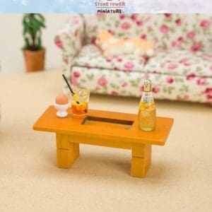Miniature coffee table with drinks, an egg, and a floral couch in the background.