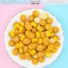 Plate of miniature pancake charms with butter slices on a pastel background.