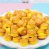 Miniature pancake stack replicas on a plate, each topped with a small butter pat.