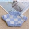 Miniature blue and white checkered knit sweater on a beige carpet with a magazine in the background.
