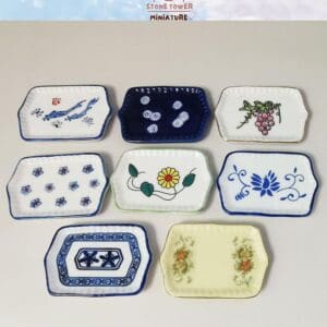 Seven rectangular miniature plates with various floral and abstract designs on a white background.