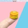 Tiny pancake stack with butter detail on a fingertip, against a pink and blue background.