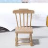 Wooden miniature chair model on a light surface with an open book in the background.