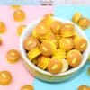 Miniature pancakes with butter, in a white bowl, on a colorful pink and blue background.