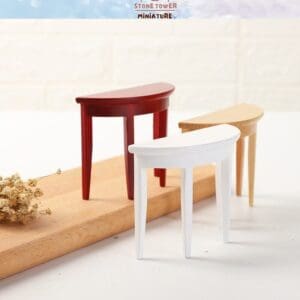 Three miniature half-moon tables in red, white, and natural wood on a wooden board with a dried flower branch.
