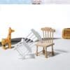 Miniature wooden scene with chairs, a giraffe figurine, and a tiny radio, on a white surface with a soft background.