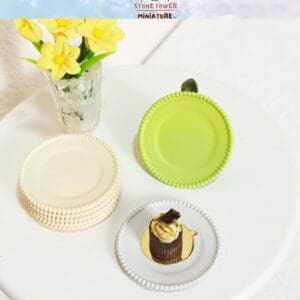Miniature yellow flowers in vase, green and white plates, and a chocolate dessert on a white surface.