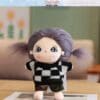 Plush doll with purple pigtails, wearing a black and white checkered sweater, stands on a table indoors.