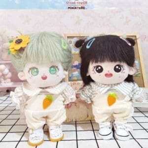 Two cute plush dolls with colorful hair, wearing carrot-themed outfits, stand on a checkered surface.