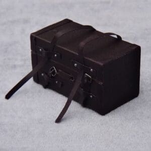 Dark brown vintage suitcase with straps and buckles, placed on a light gray surface.