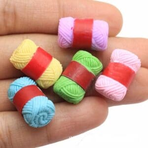 Five colorful miniature yarn bundles with red bands on a hand.
