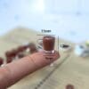 Miniature coffee cup with dimensions on fingertip: 15mm wide, 12mm tall, 9mm deep.