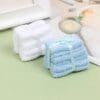 Two stacks of folded washcloths, one white and one blue, tied with ribbons on a light green surface.