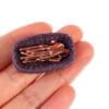 Tiny purple basket with miniature copper utensils held in a person's hand.