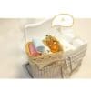 Miniature bathroom scene with towels, a gold mirror, and toiletries in a woven basket near a sink with a plaid skirt.