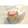 Miniature bathroom set with pink towel, various bottles, and accessories in a small basket on a white sink.