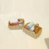 Two small baskets with lace edges containing miniature bath supplies like towels and bottles on a cream background.