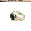 Gold ring with black circular face featuring a stylized face and textured band design.