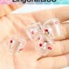 Hand holding four clear dice with cherry patterns.