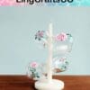 Glass cups with pink rose designs on a white tree stand, by LingCraftsCO, against a light blue background.