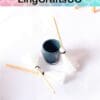 Miniature cleaning set with a small bucket and two tiny brooms on a white surface.