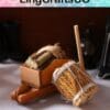 Miniature cheese press and churn made of wood and straw, with twine, on a white surface with blurred background.