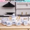 Miniature blue and white porcelain tea set displayed on a wooden table in a dollhouse kitchen.