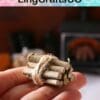 A hand holding a small bundle of miniature firewood tied with twine, with a blurred stove in the background.