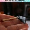 Hand holding a small black axe-like miniature model with a wooden handle.