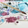 Watercolor paint tubes, a brush, and a palette with mixed colors on a table.