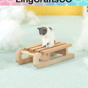 Miniature cat figurine on a wooden sled surrounded by fluffy clouds, with a decorative LingCraftsCO banner above.