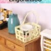 Miniature wooden cabinet with yellow basket, cup, and blue jug on top, vintage telephone in background.