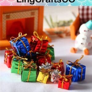 Colorful miniature gift boxes with gold bows arranged on a table near a toy fireplace and snowman.