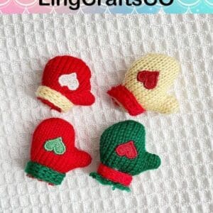 Four small knitted mittens with heart designs on a textured white background.