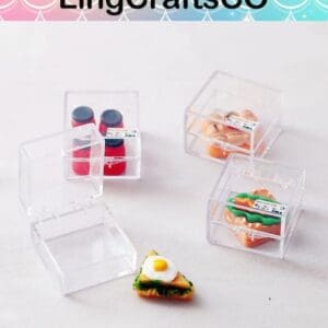 Clear boxes with miniature food items, including bottles, pastries, and a sandwich, on a light surface.