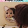 Doll reflected in a round, bear-shaped mirror on a table with a hairbrush and a decorative item.