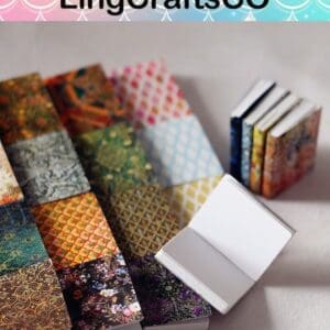 Colorful miniature notebooks with intricate designs, displayed open and closed on a plain surface.