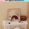 Miniature vanity with a mirror, perfume bottle, hairdryer, and wooden box on a white table.